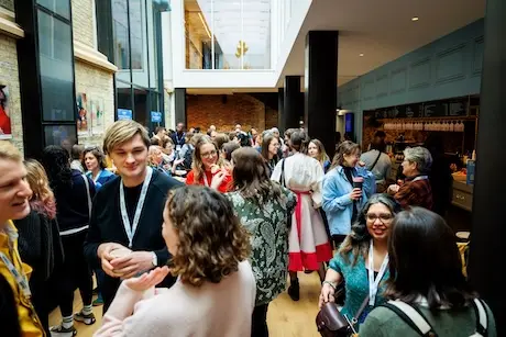 Groups of people having conversations during a break in a light airy space.